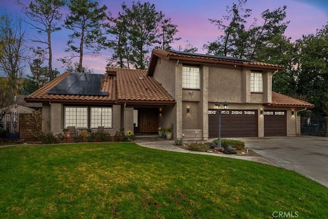 mediterranean / spanish home featuring a garage, a yard, and solar panels