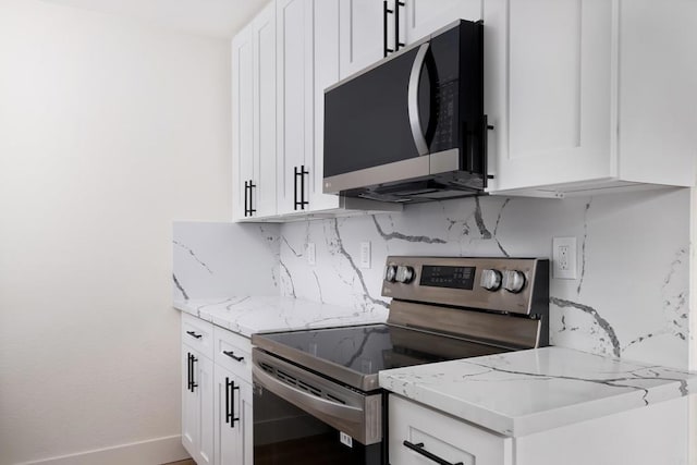 kitchen with stainless steel electric range oven, white cabinets, and light stone counters