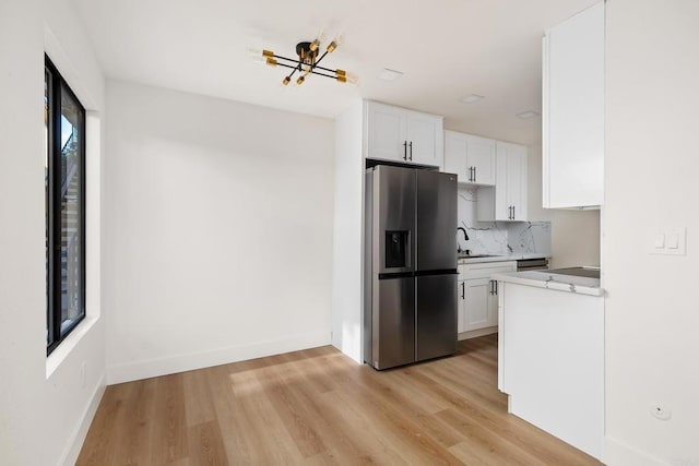 kitchen featuring white cabinetry, backsplash, stainless steel fridge, and light hardwood / wood-style floors