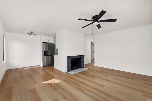 unfurnished living room with ceiling fan, a fireplace, and light hardwood / wood-style flooring