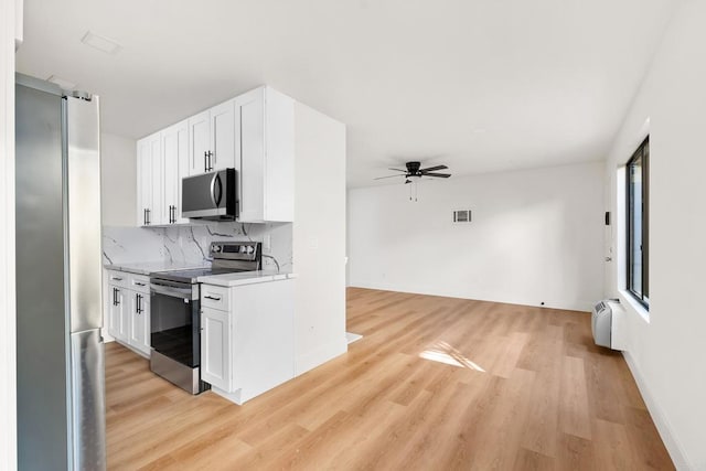 kitchen featuring white cabinetry, tasteful backsplash, ceiling fan, stainless steel appliances, and light hardwood / wood-style floors