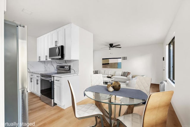 dining room with ceiling fan and light wood-type flooring