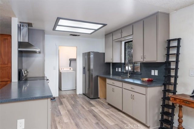 kitchen with sink, washer / clothes dryer, decorative backsplash, wall chimney exhaust hood, and light wood-type flooring