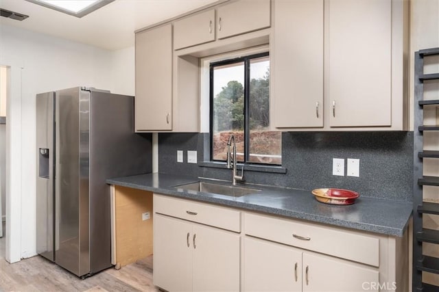 kitchen featuring stainless steel refrigerator with ice dispenser, light hardwood / wood-style floors, sink, and decorative backsplash