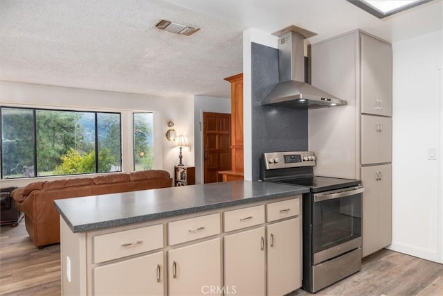 kitchen with wall chimney exhaust hood, stainless steel range with electric stovetop, a textured ceiling, light wood-type flooring, and kitchen peninsula