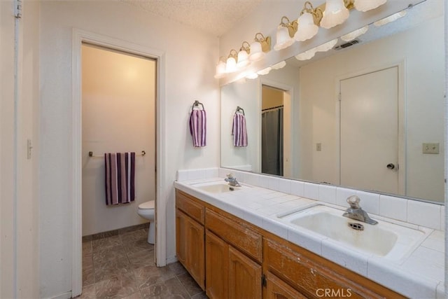 bathroom featuring vanity, toilet, and a textured ceiling