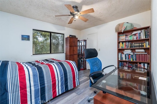 bedroom with ceiling fan, a textured ceiling, and light wood-type flooring