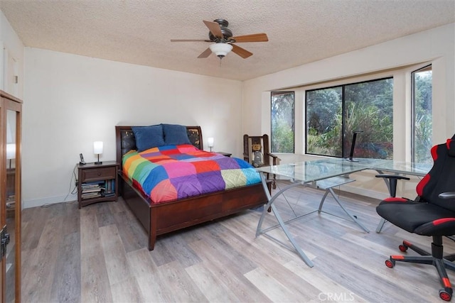 bedroom with ceiling fan, a textured ceiling, and light hardwood / wood-style floors