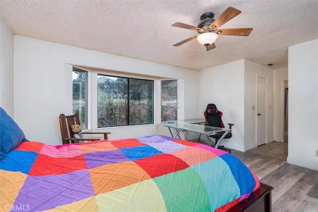 bedroom featuring ceiling fan, hardwood / wood-style floors, and a textured ceiling