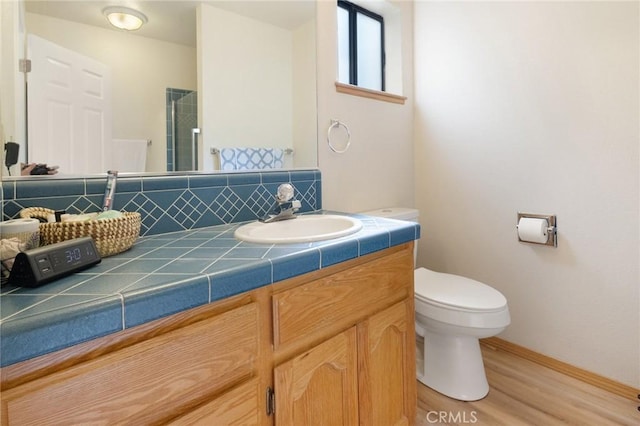 bathroom featuring vanity, hardwood / wood-style flooring, tasteful backsplash, and toilet