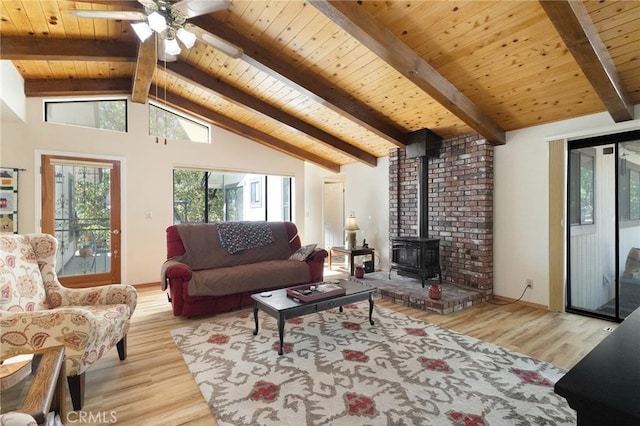 living room with a wood stove, vaulted ceiling with beams, wooden ceiling, and light hardwood / wood-style flooring