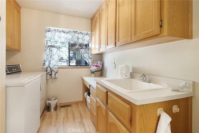 laundry room with cabinets, washer / dryer, sink, and light hardwood / wood-style floors