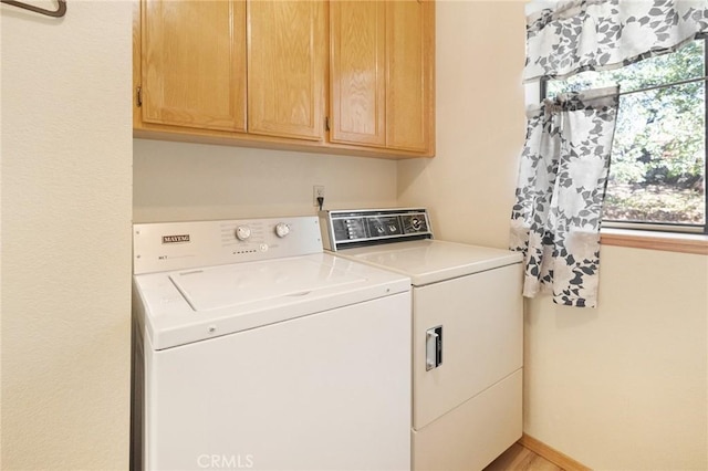 clothes washing area featuring washer and dryer and cabinets