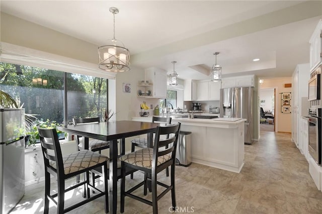 dining area with an inviting chandelier, sink, and a tray ceiling