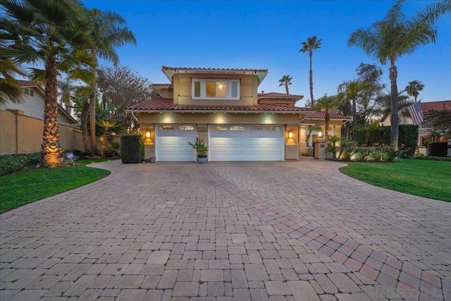 mediterranean / spanish-style home featuring a garage and a yard