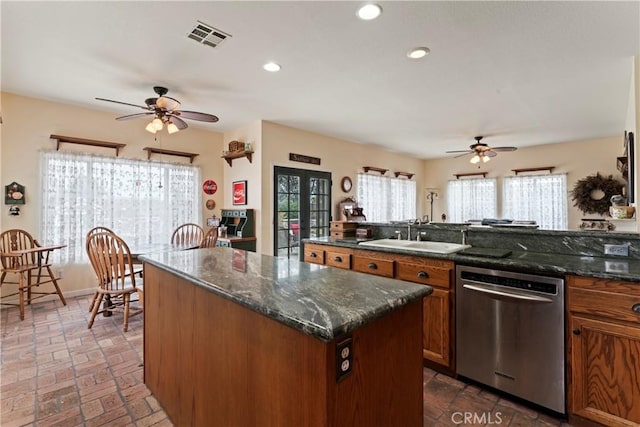 kitchen featuring french doors, sink, dishwasher, a kitchen island, and dark stone counters