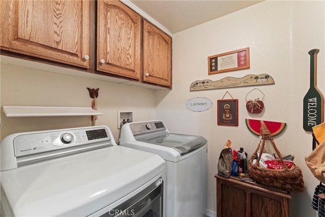 clothes washing area with cabinets and washer and clothes dryer