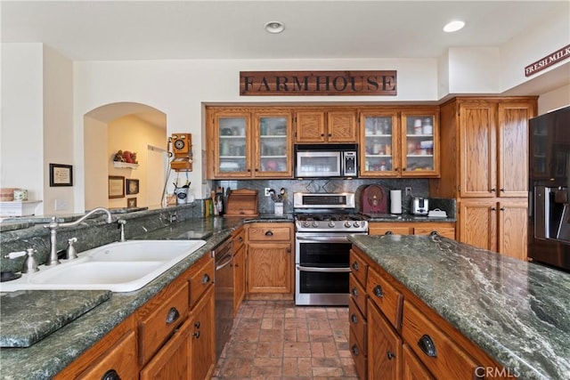 kitchen featuring dark stone countertops, sink, backsplash, and stainless steel appliances