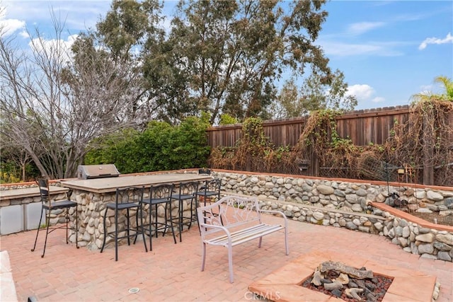 view of patio with a bar, an outdoor kitchen, area for grilling, and a fire pit