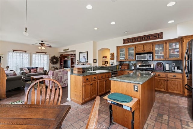 kitchen featuring tasteful backsplash, sink, hanging light fixtures, kitchen peninsula, and stainless steel appliances