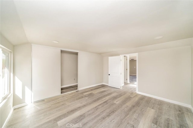 spare room with vaulted ceiling and light wood-type flooring