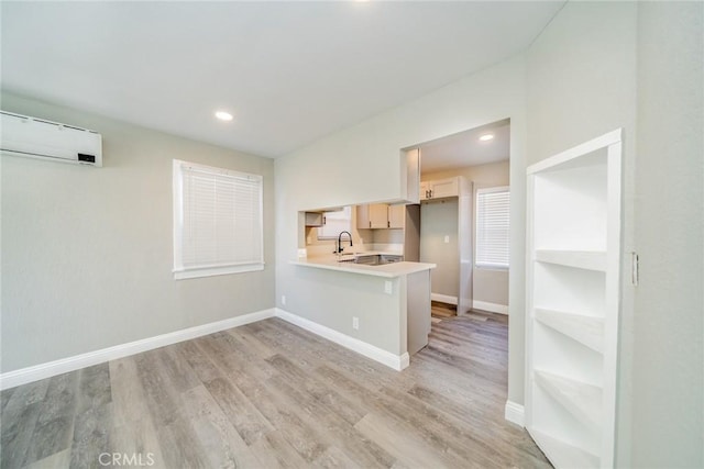 kitchen with light wood-type flooring, sink, a kitchen breakfast bar, and kitchen peninsula