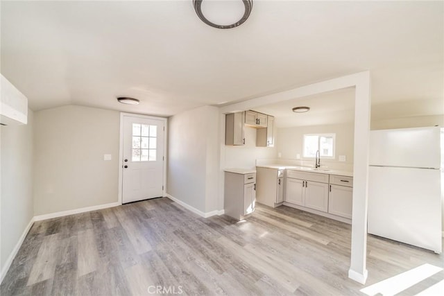 interior space featuring lofted ceiling, sink, and light wood-type flooring