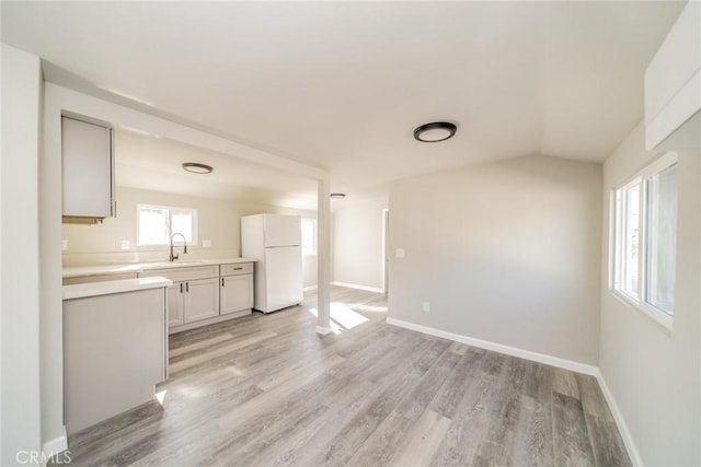 interior space featuring white refrigerator, sink, white cabinets, and light hardwood / wood-style floors