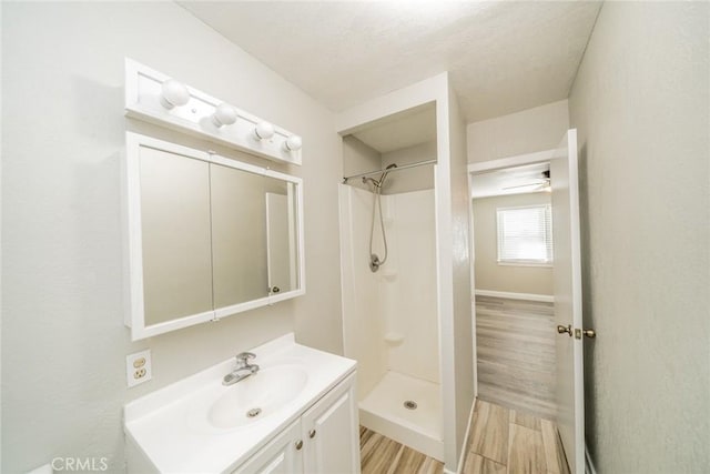 bathroom with hardwood / wood-style flooring, vanity, and walk in shower