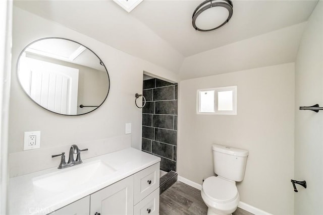 bathroom featuring vanity, hardwood / wood-style flooring, toilet, and tiled shower