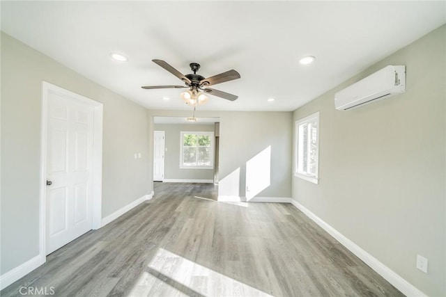 unfurnished living room featuring an AC wall unit, ceiling fan, and light hardwood / wood-style flooring