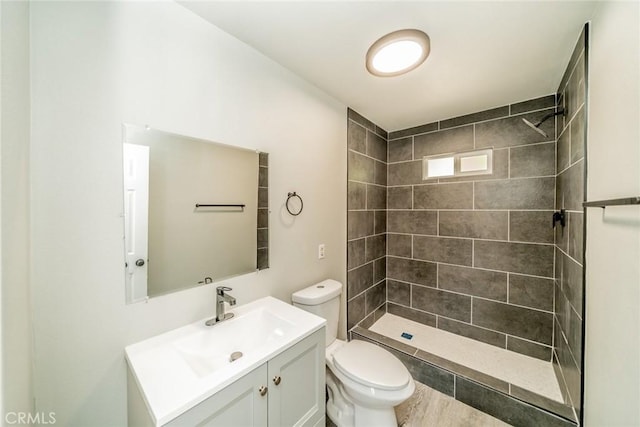 bathroom with tiled shower, vanity, and toilet