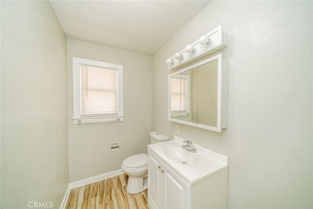 bathroom with wood-type flooring, toilet, vanity, and a wealth of natural light