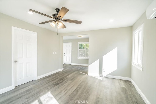 empty room with ceiling fan, light hardwood / wood-style flooring, and an AC wall unit