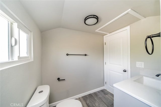 bathroom featuring hardwood / wood-style floors, vaulted ceiling, sink, and toilet