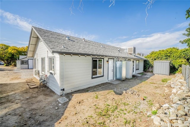 rear view of property featuring a storage unit and central AC unit