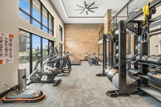 workout area featuring a towering ceiling and wood walls