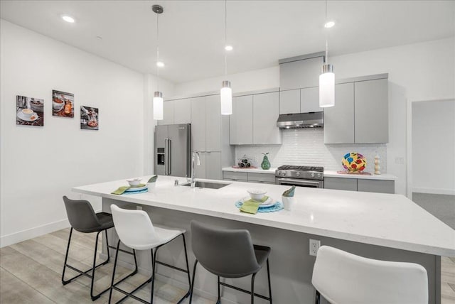 kitchen featuring sink, gray cabinets, a breakfast bar, premium appliances, and a large island with sink