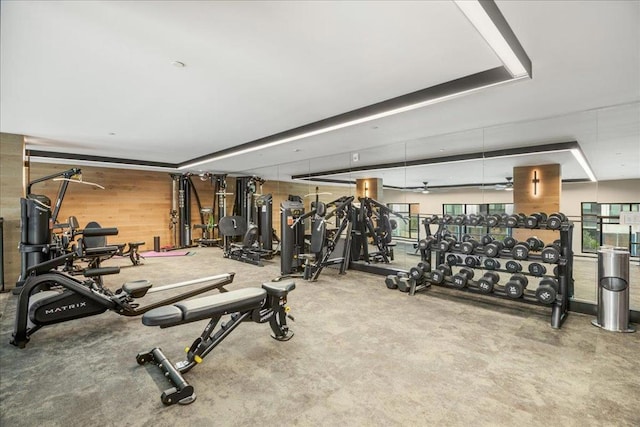 workout area featuring a tray ceiling and wooden walls