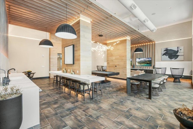 dining space with a towering ceiling, sink, and wood walls