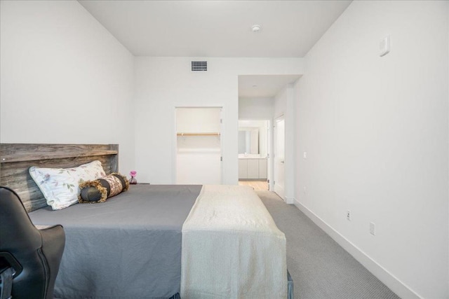 carpeted bedroom with a spacious closet and ensuite bath