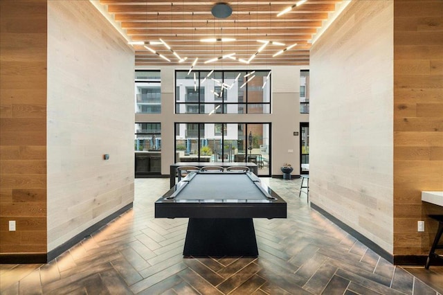 rec room featuring parquet floors, a towering ceiling, pool table, and wood walls