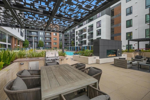 view of patio featuring area for grilling, a fireplace, and a pergola