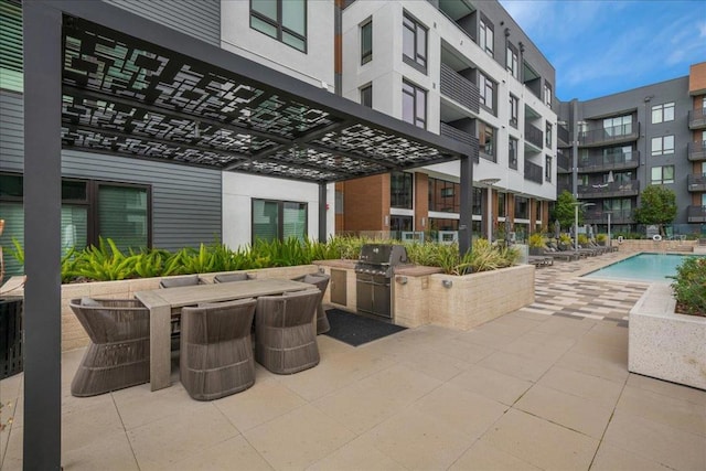 view of patio with an outdoor kitchen, a community pool, and a grill