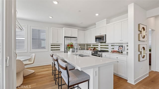 kitchen featuring white cabinetry, appliances with stainless steel finishes, sink, and a center island with sink