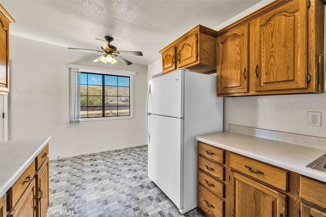 kitchen with a textured ceiling, ceiling fan, and white refrigerator