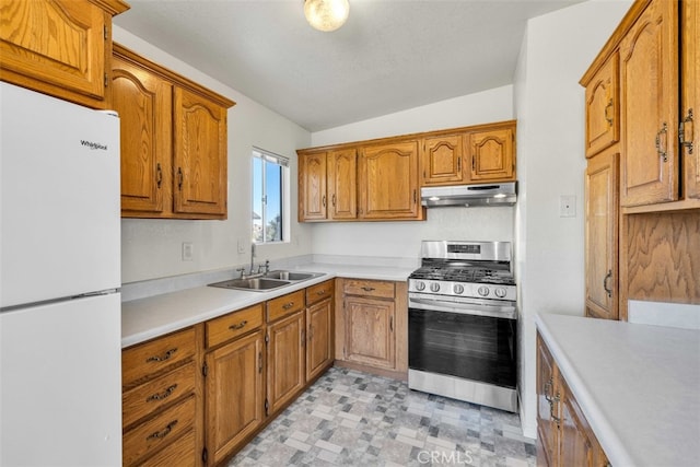 kitchen with white refrigerator, stainless steel range with gas cooktop, sink, and lofted ceiling