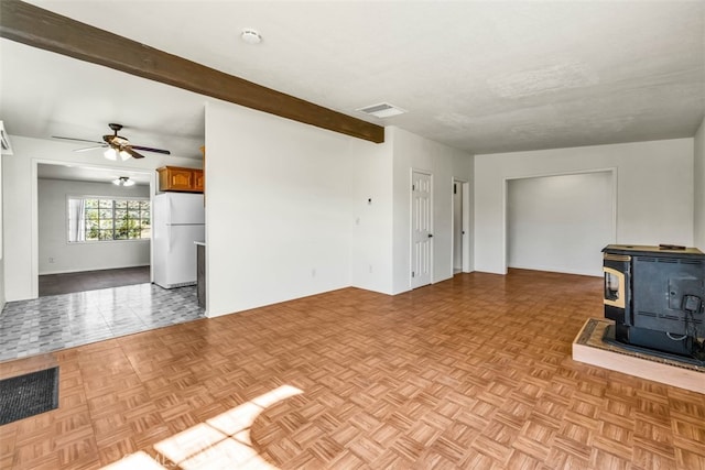 unfurnished living room with light parquet flooring, a wood stove, ceiling fan, and beam ceiling