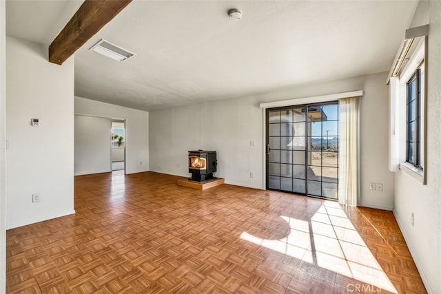 unfurnished living room featuring beamed ceiling, light parquet flooring, and a wood stove