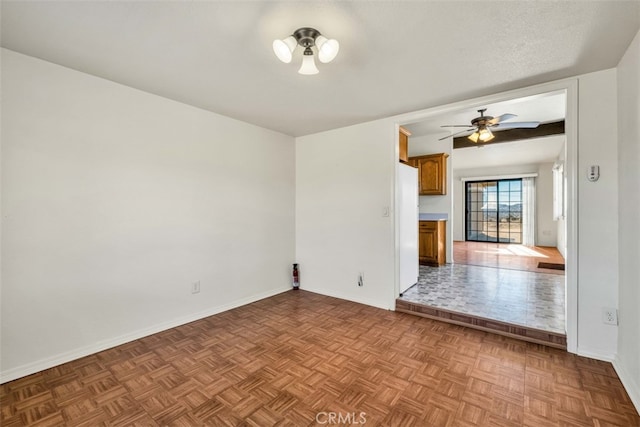 unfurnished room with ceiling fan, light parquet flooring, and a textured ceiling